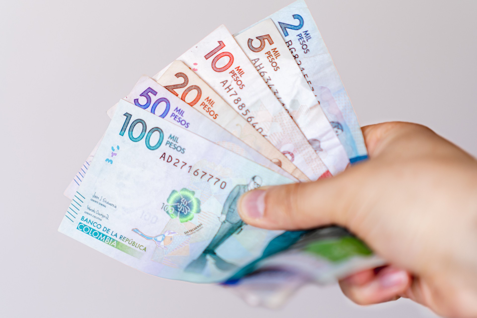 Foto einer Hand, die verschiedene kolumbianische Banknoten unterschiedlicher Stückelungen hält